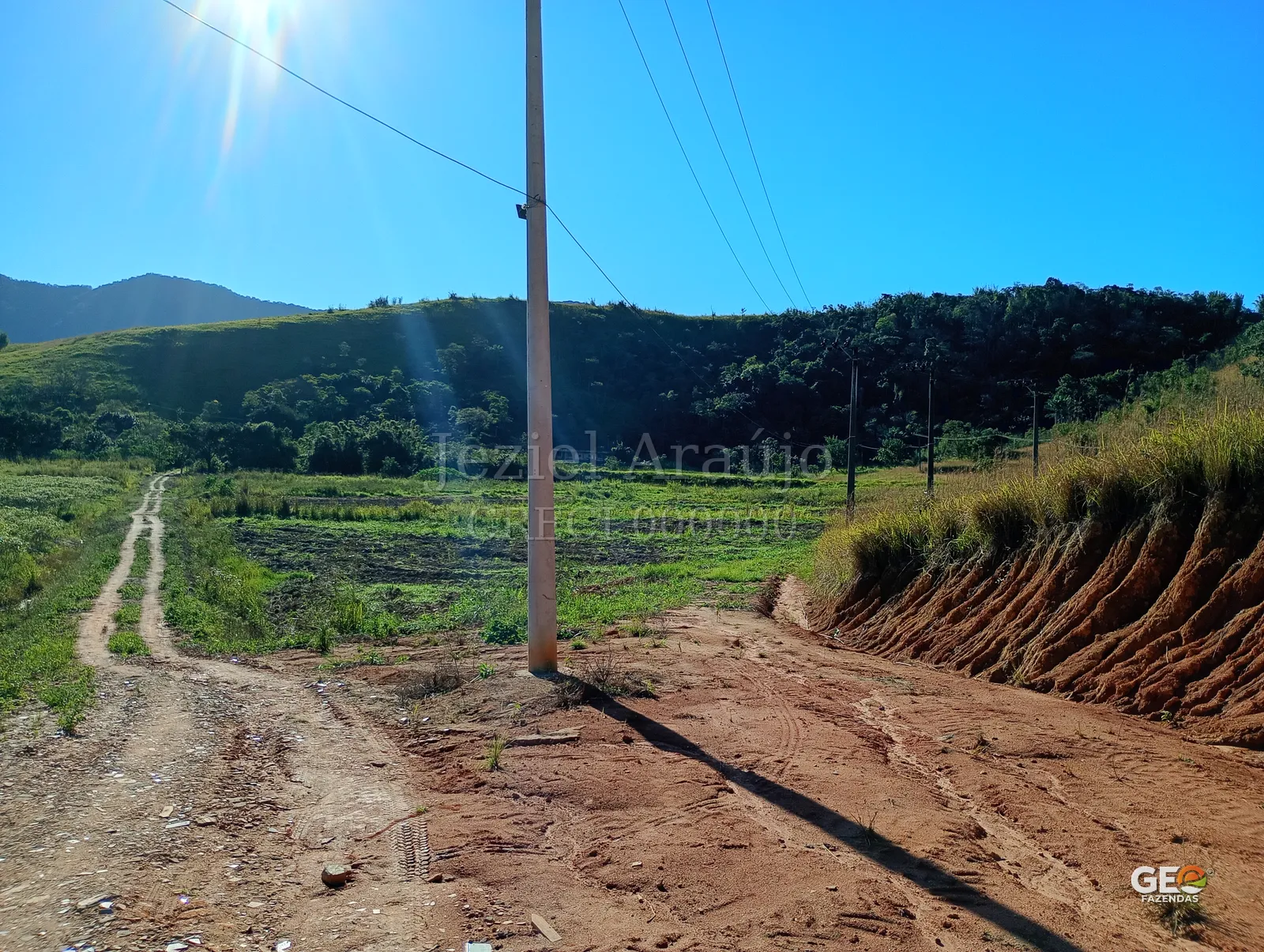 Área rural com estrada e postes de energia
