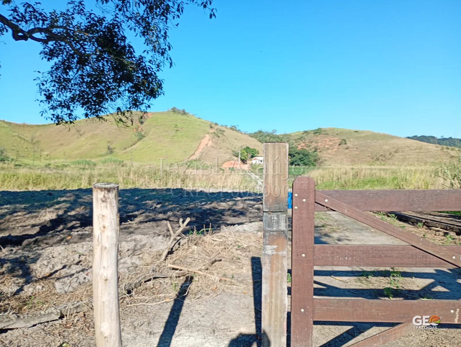 Entrada de fazenda com porteira e colina ao fundo