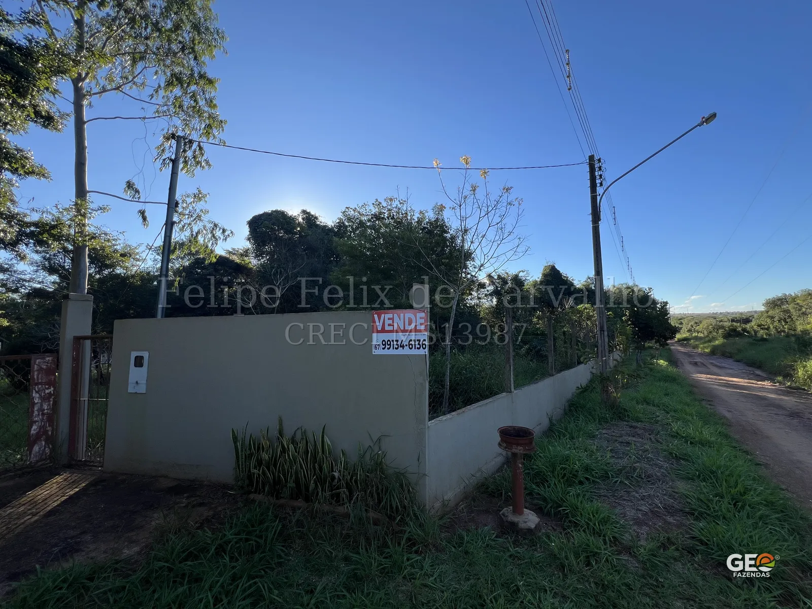Terreno rural com placa de venda e vegetação