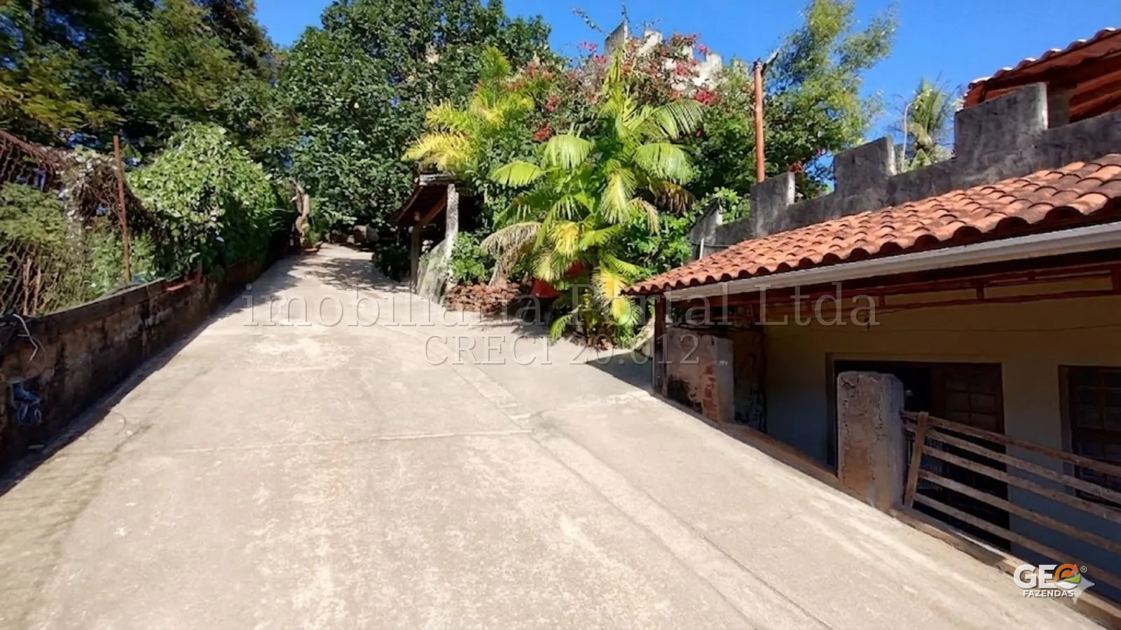Entrada de propriedade rural com vegetação e construção