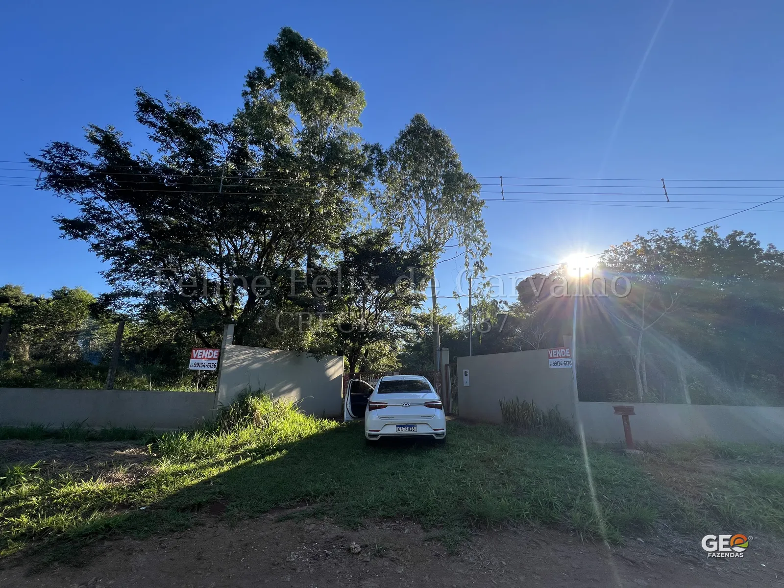 Entrada de propriedade rural com carro e muro