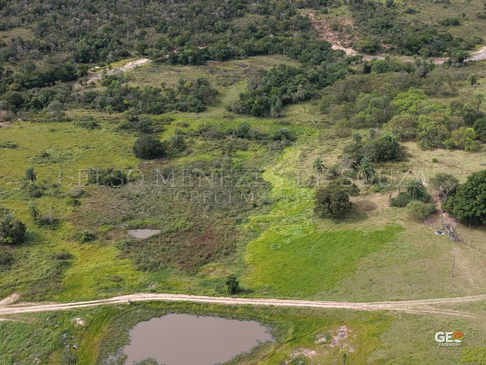 Área rural com pastagem, vegetação e lagoa